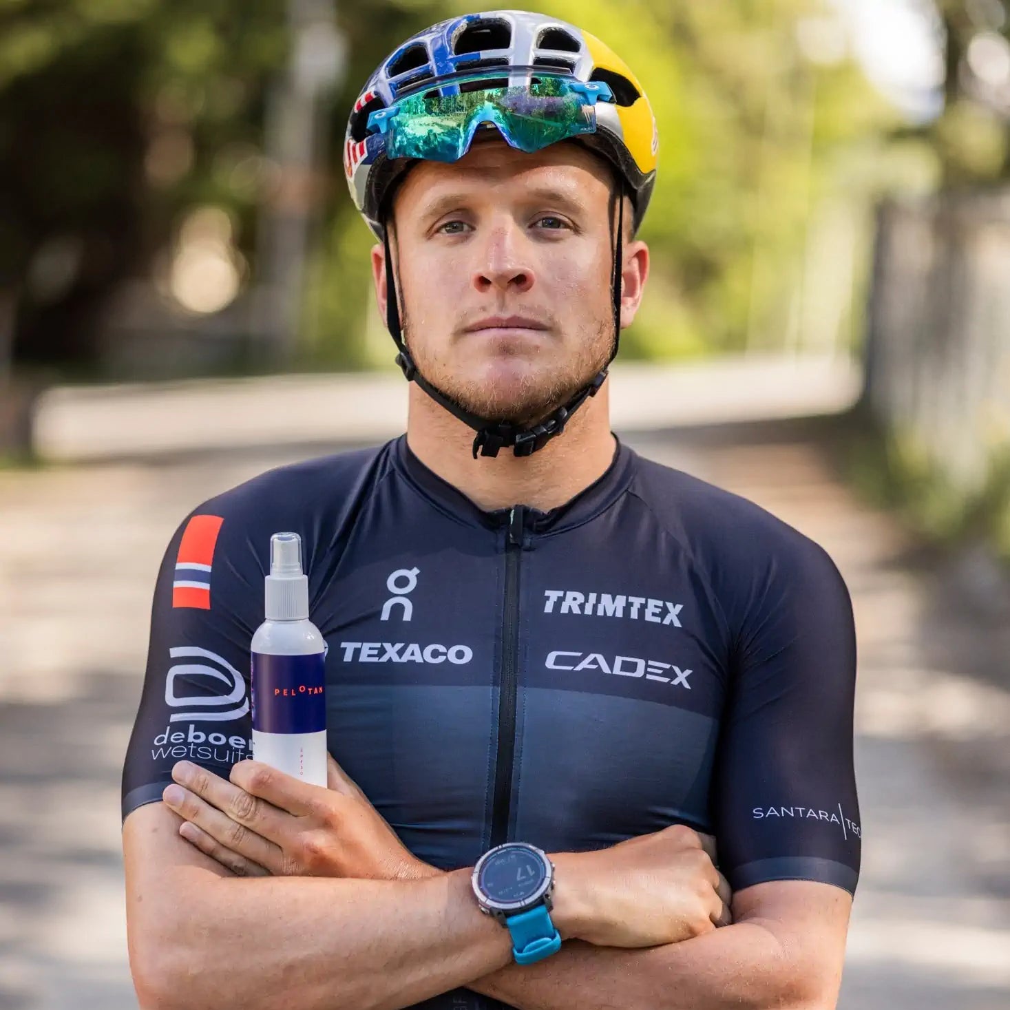 Cyclist holding a bottle with sponsor logos on a blurred outdoor background