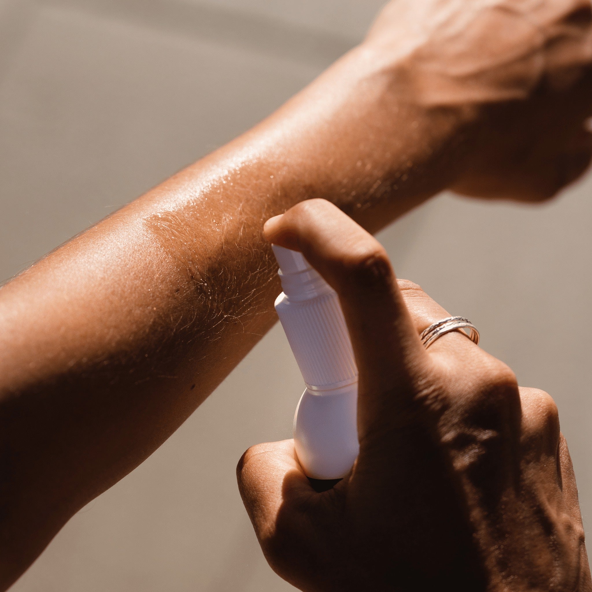 An athletes is applying a spray of Pelotan to their other arm.