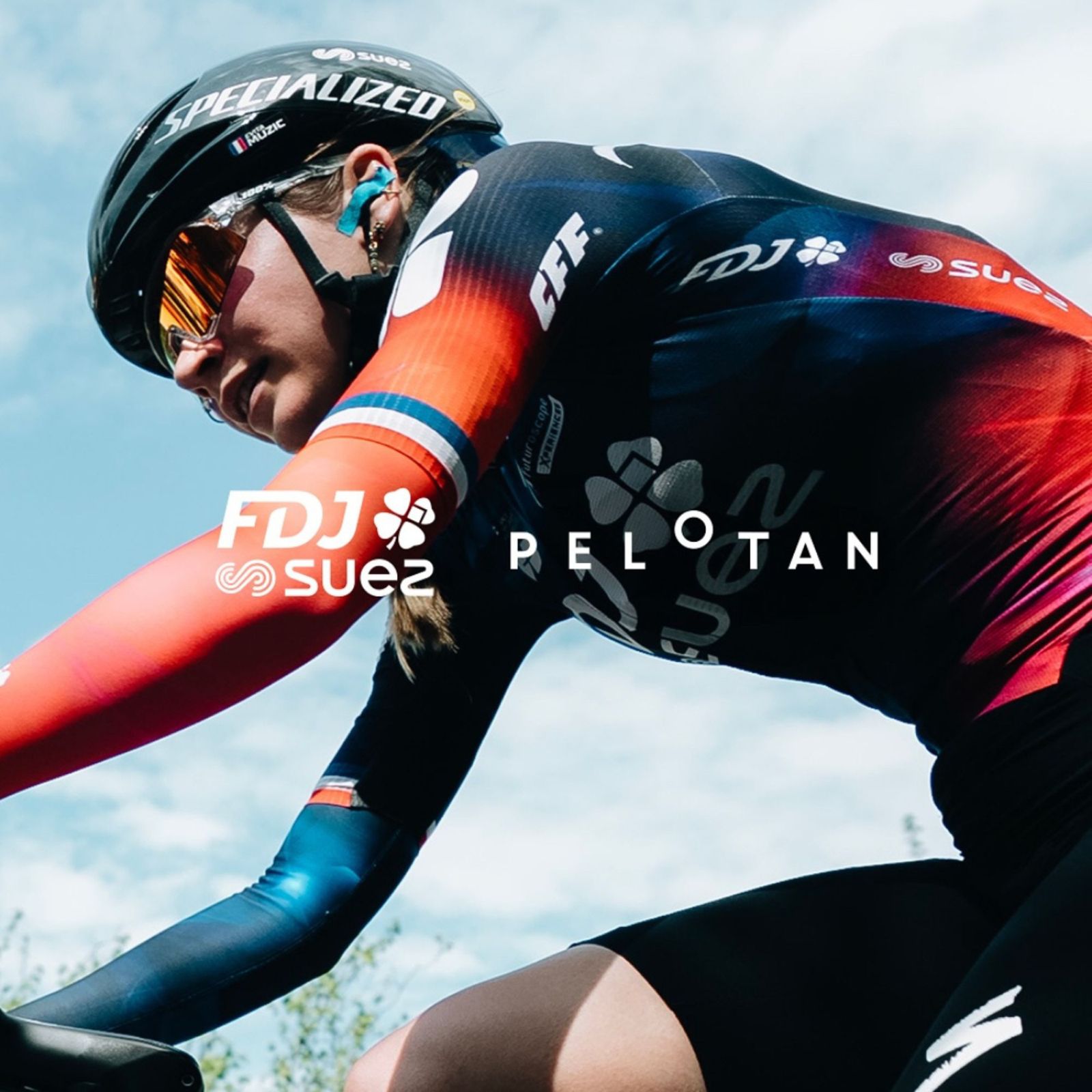Cyclist in action with visible branding on clothing against a sky background
