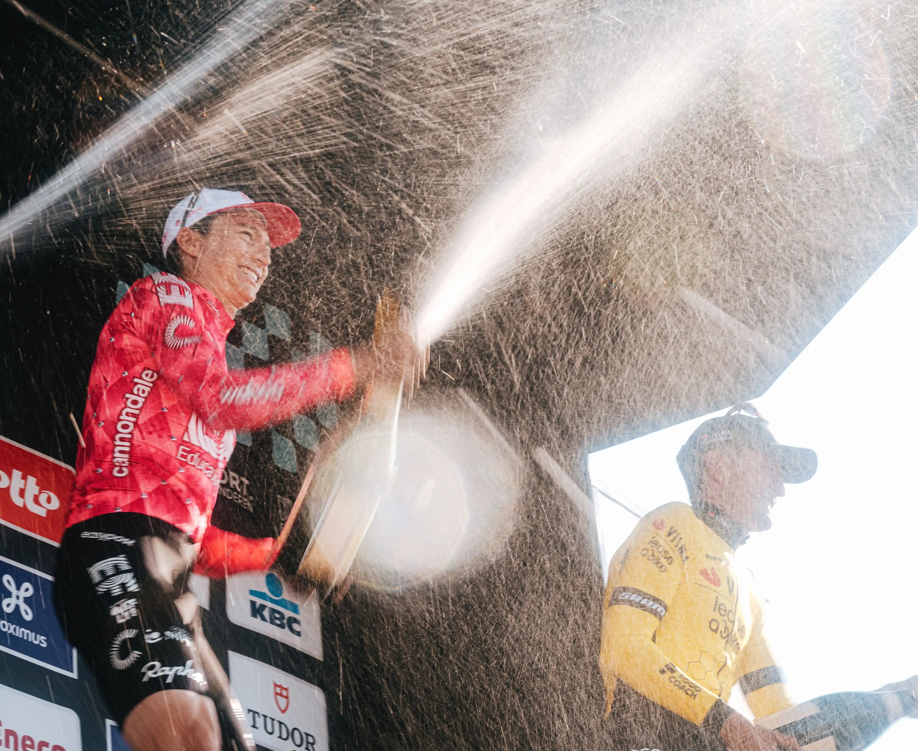 EF Pro Cyclist in a pink jersey celebrating with champagne at a podium