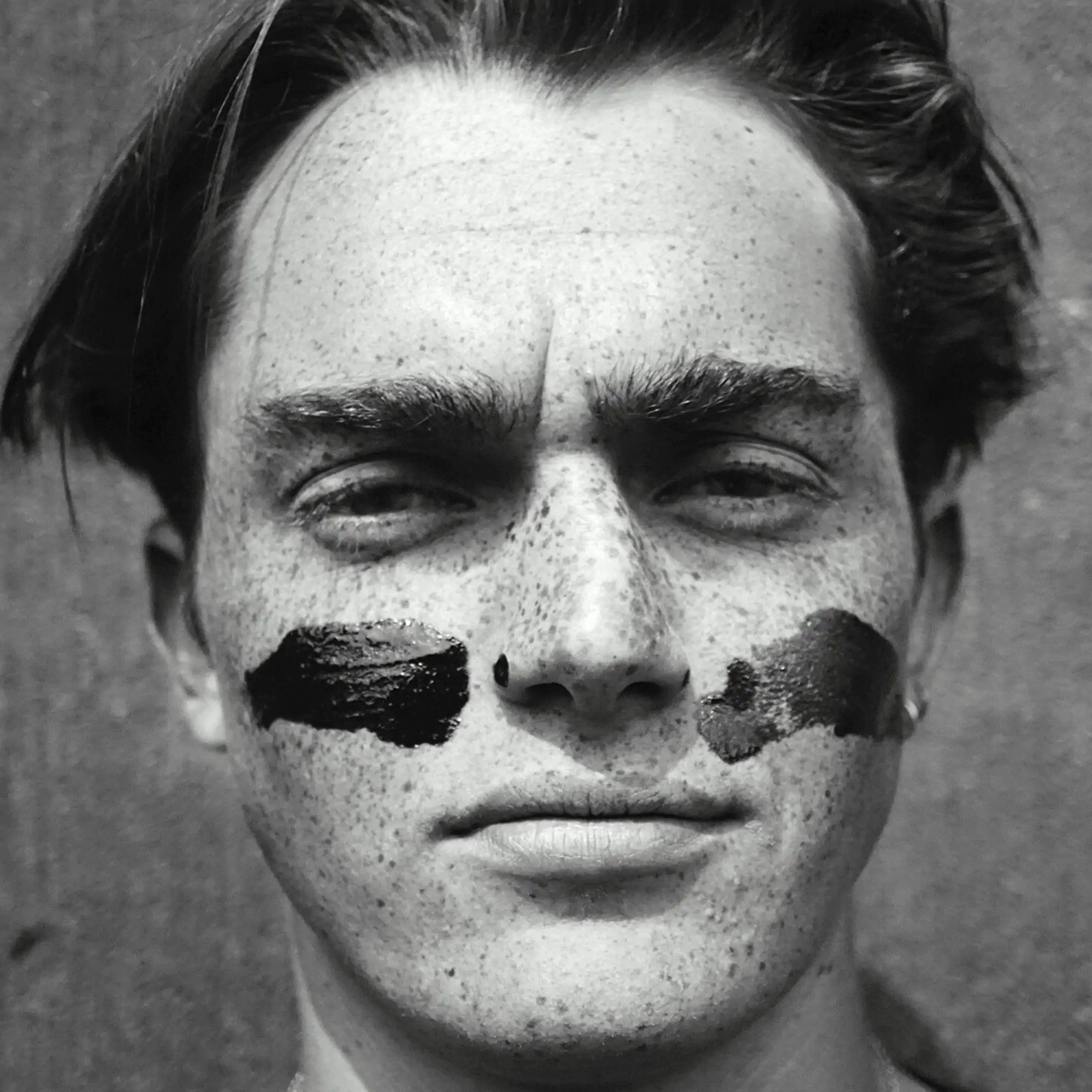 UV camerage photo of an athlete after applying Pelotan sunscreen across their cheeks, with dark black areas showing the sun protection from the UV camera’s light source.