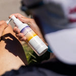 An athlete is sat in the sun applying Pelotan Après Recovery gel.