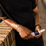 A photo of a tanned athlete holding a bottle of Pelotan sports sunscreen
